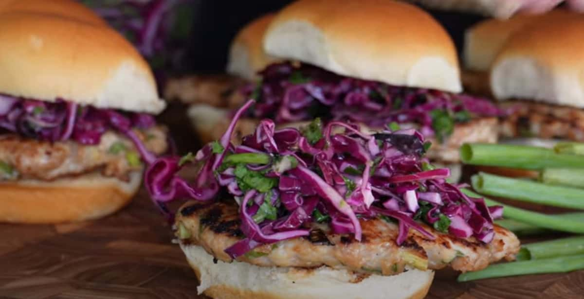 A close-up of a grilled chicken sandwich on a wooden surface